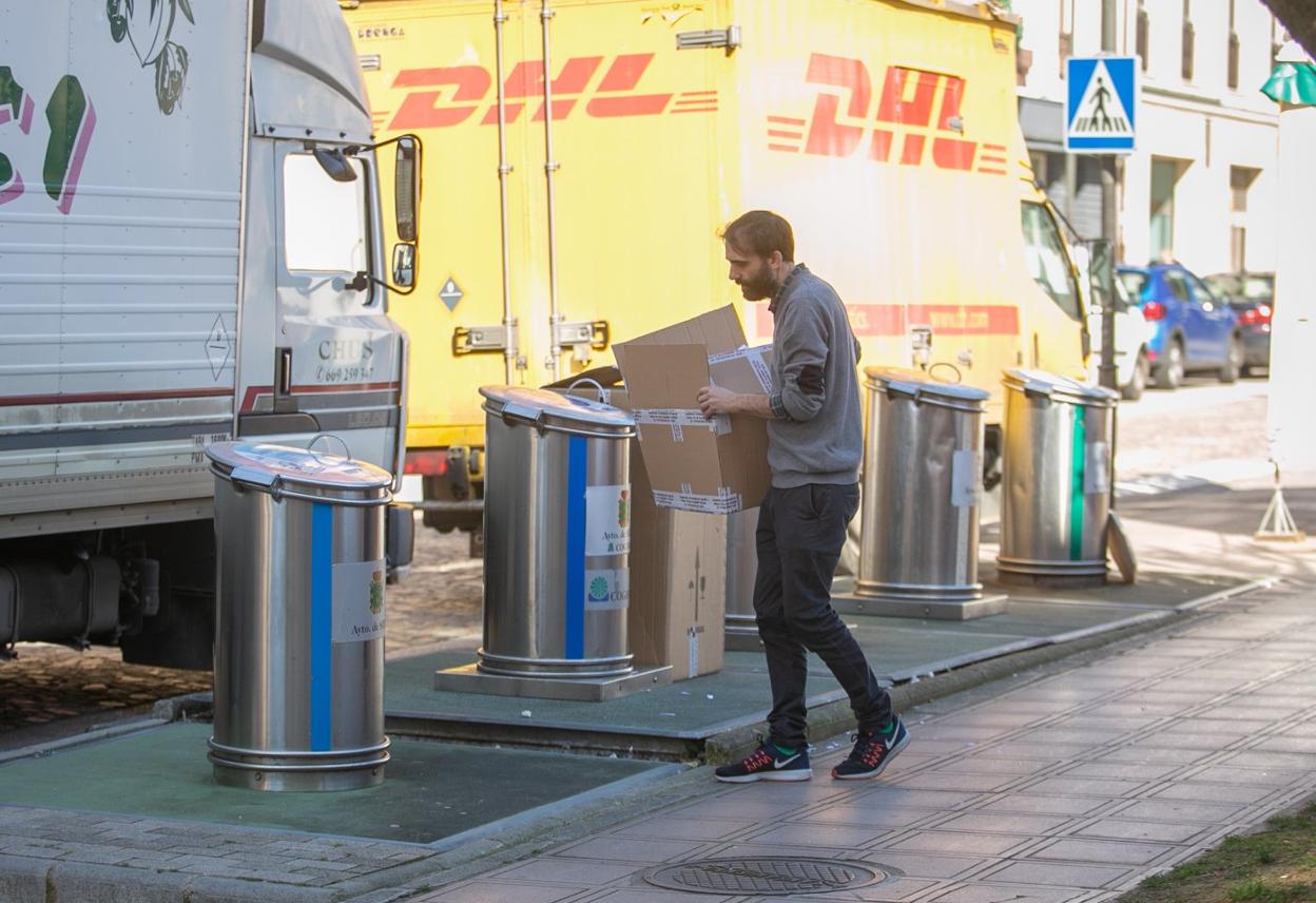 Un vecino de la Pola se acerca a los contenedores de reciclaje para depositar una caja de cartón. 