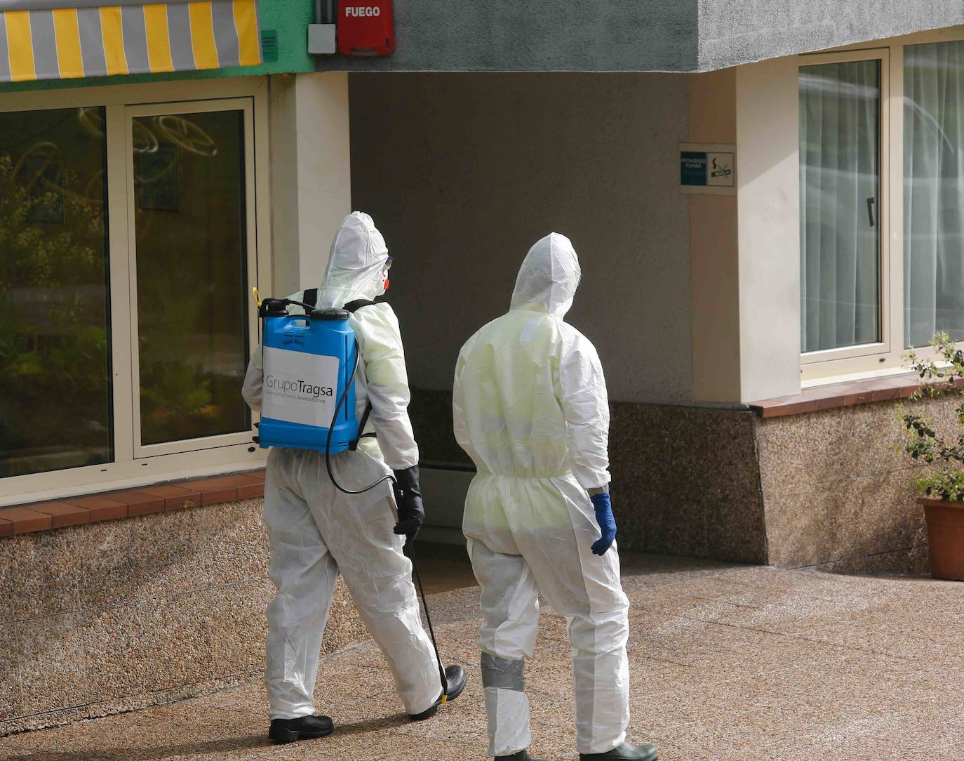 Trabajadores y personal de Tragsa desinfectan las instalaciones de la residencia del ERA en Grado.