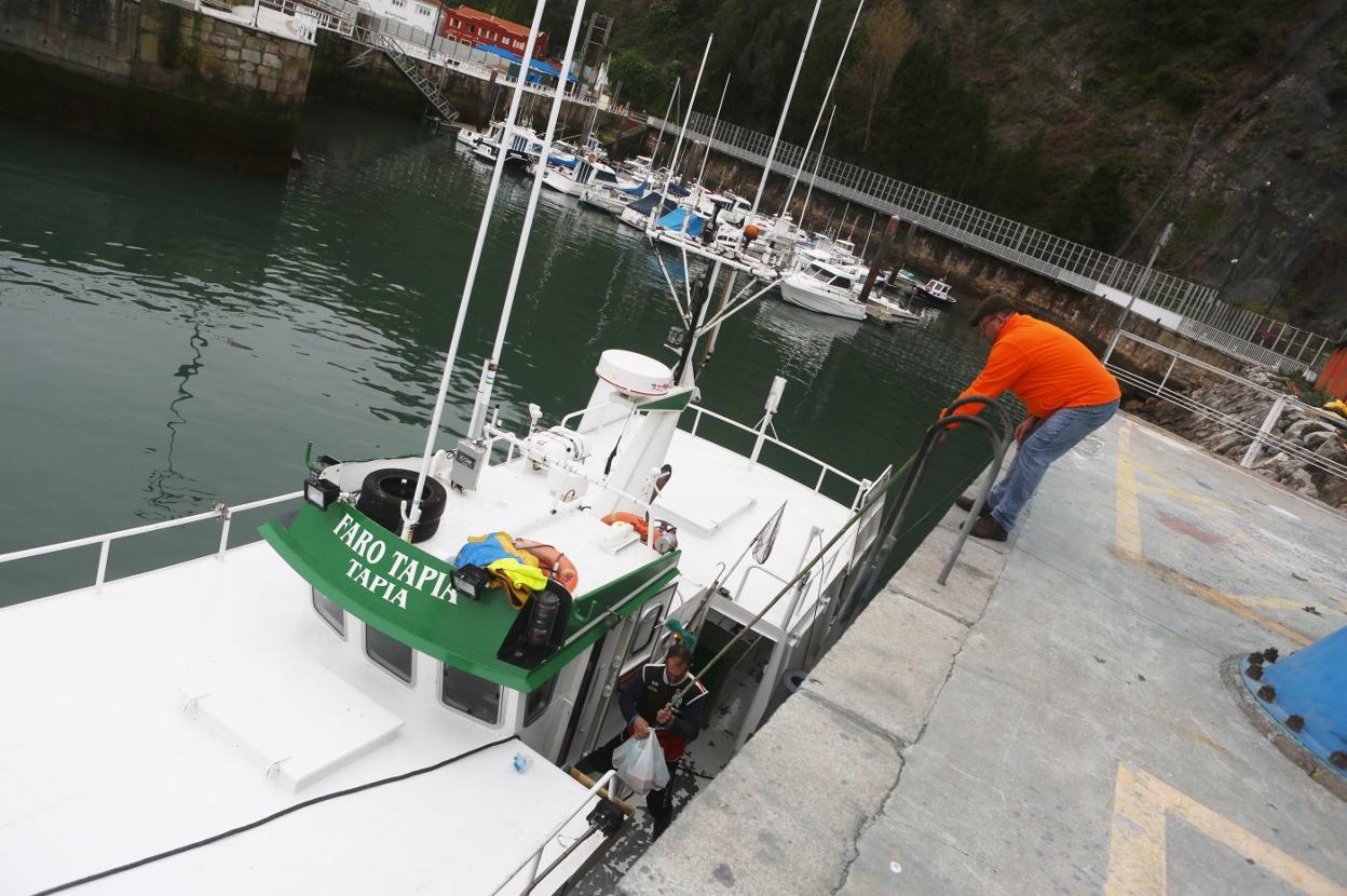 Otto Gutiérrez entrega la comida a los marineros del 'Faro de Tapia' en el puerto llastrín. 