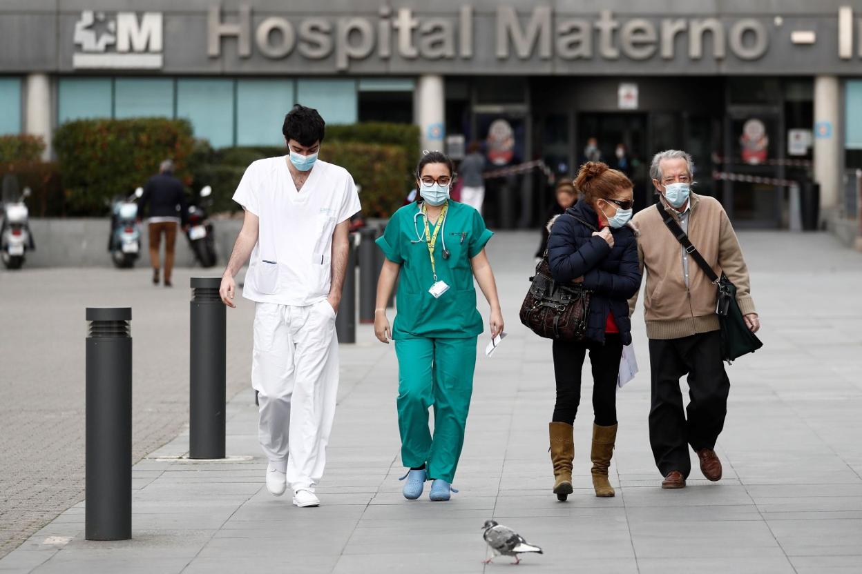 Dos sanitarios, a la salida de un hospital, sin retirar sus mascarillas. 