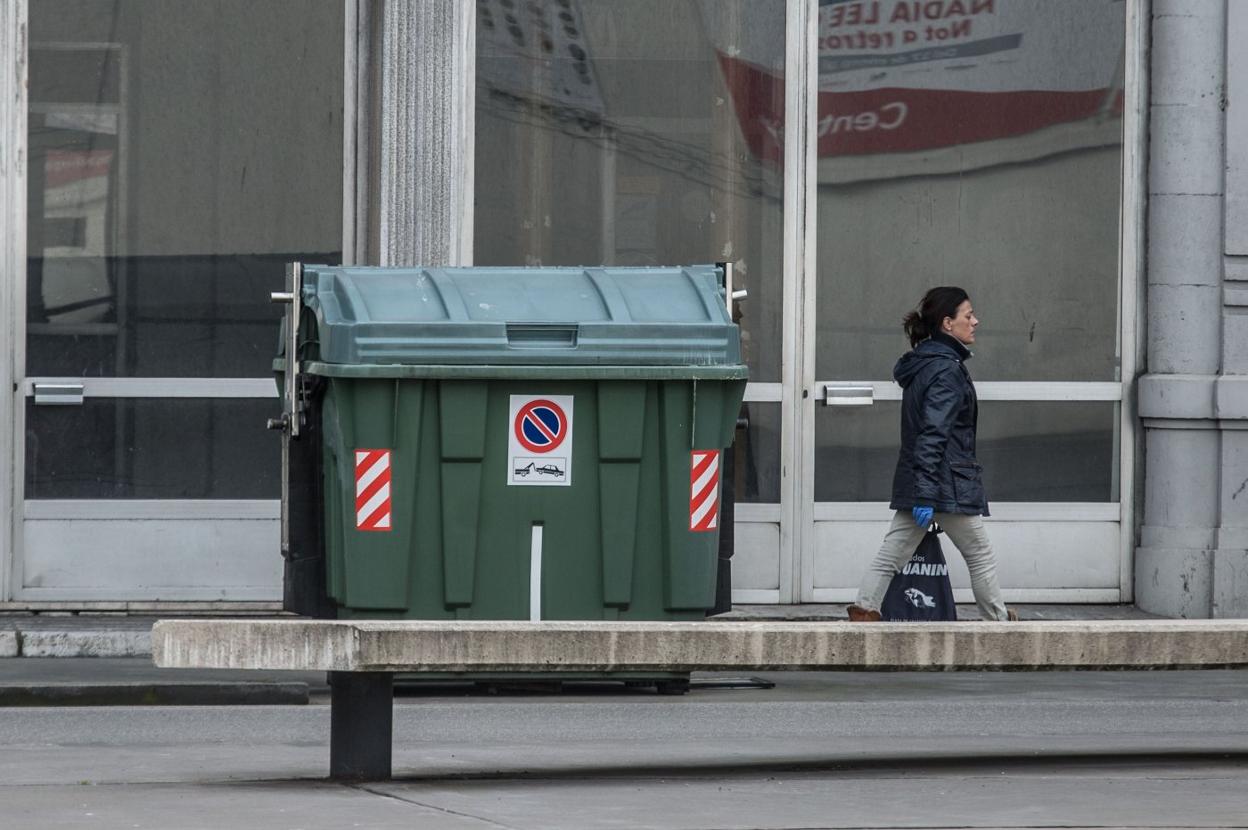 Una viandante pasa junto a un contenedor de residuos urbanos, en la calle Llano Ponte. 