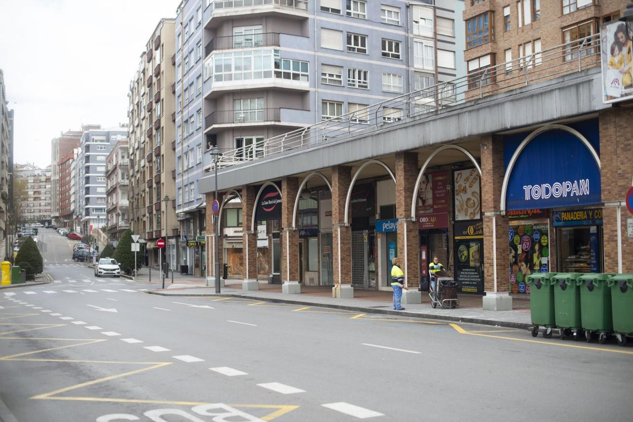 Dos empleados del servicio de limpieza conversan en una calle Jardines con los locales cerrados y aspecto de domingo por la mañana. 