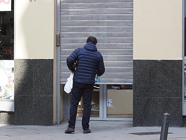 Un comerciante cierra la persiana de su negocio. 