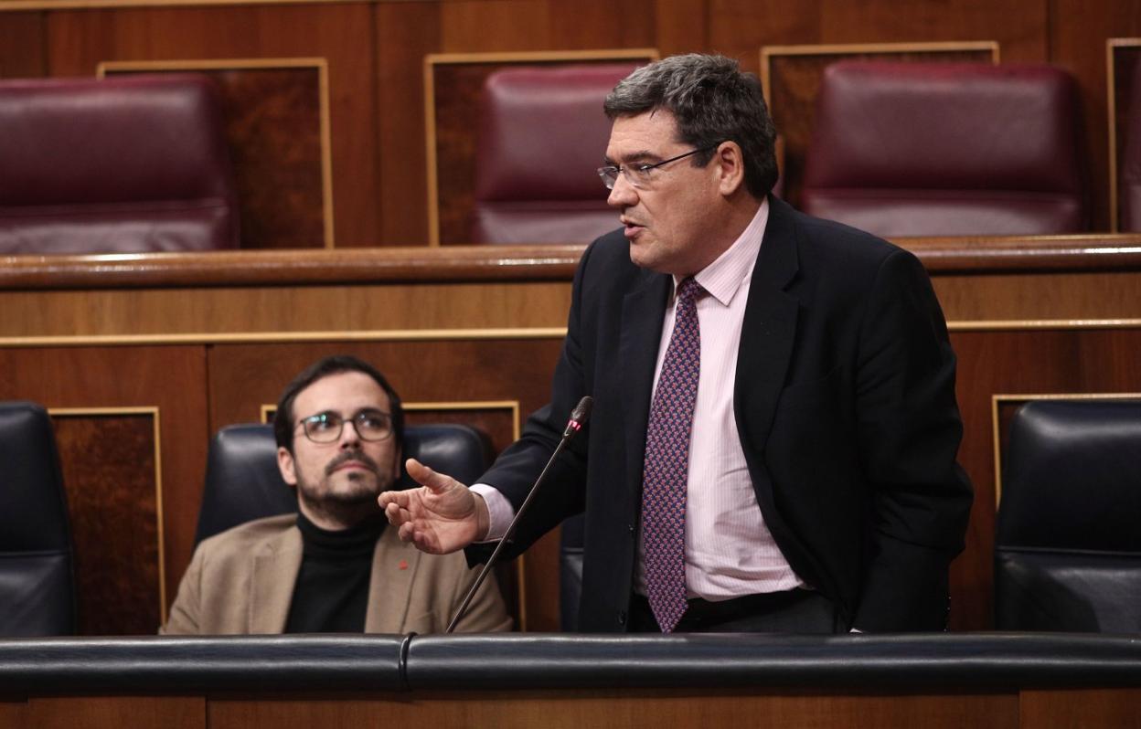 El ministro José Luis Escrivá, durante una comparecencia en el Congreso, observado por el titular de Consumo, Alberto Garzón. 