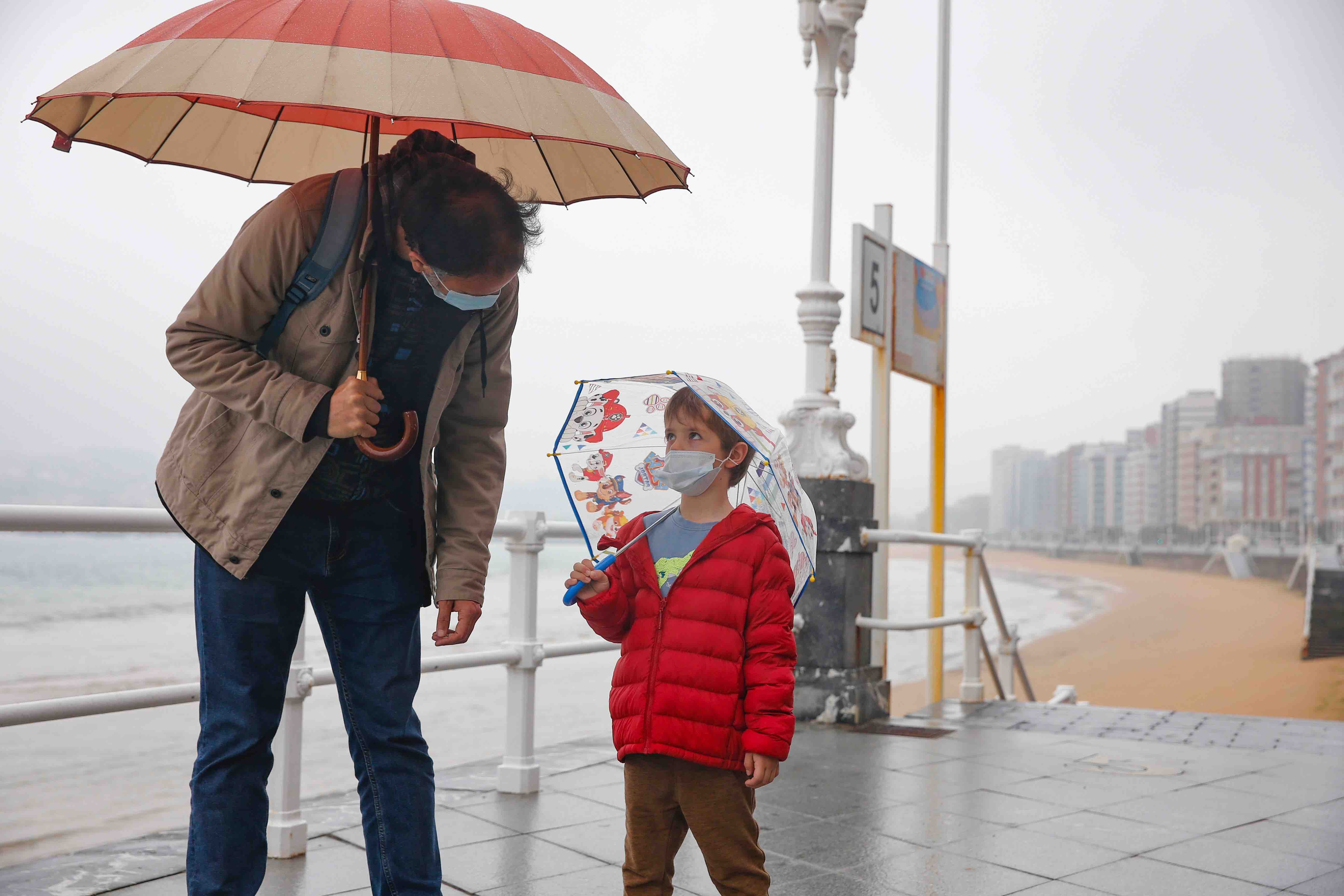 Primeros paseos bajo el orbayu en Gijón de los más pequeños