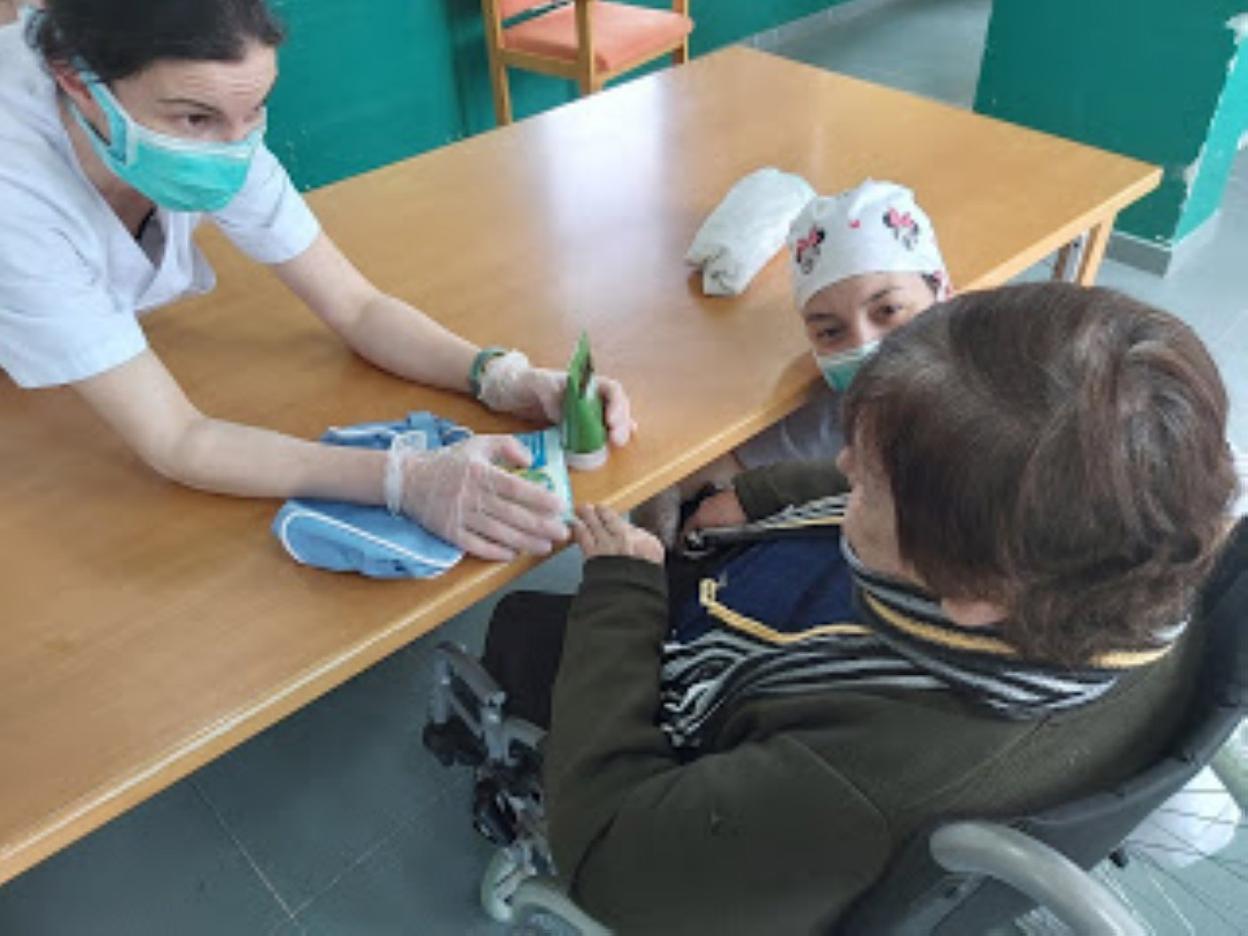 Dos trabajadoras entregan a una residente un lote de productos de higiene.