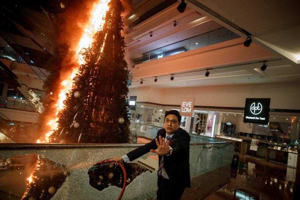 Un trabajador de seguridad pide precaución mientras arde un árbol de Navidad en el centro comercial en Kowloon Tong en Hong Kong, el 12 de noviembre de 2019. Autor: THOMAS PETER (REUTERS)