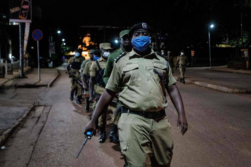 Varios policías ugandeses y miembros de una fuerza paramilitar compuesta por civiles patrullan por las noches en la ciudad de Kampala para asegurarse del cumplimiento del toque de queda nocturno decretado el 14 de abril en Uganda para tratar de detener la propagación del coronavirus. 