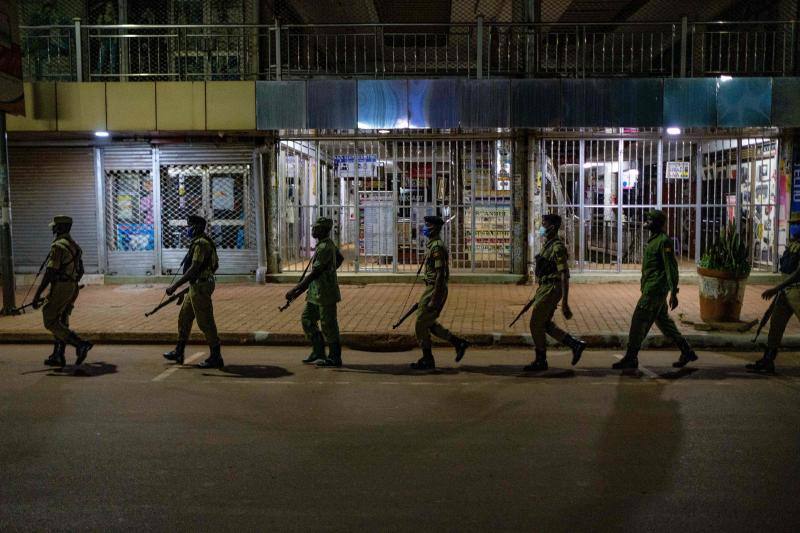 Varios policías ugandeses y miembros de una fuerza paramilitar compuesta por civiles patrullan por las noches en la ciudad de Kampala para asegurarse del cumplimiento del toque de queda nocturno decretado el 14 de abril en Uganda para tratar de detener la propagación del coronavirus. 