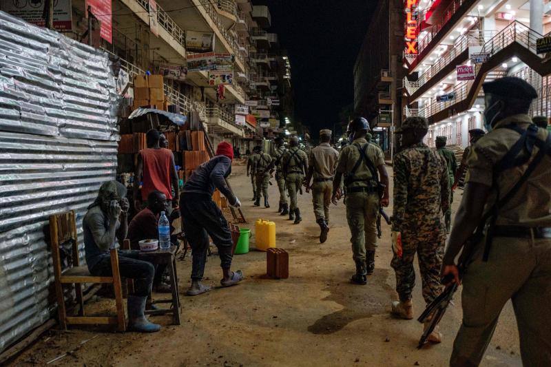 Varios policías ugandeses y miembros de una fuerza paramilitar compuesta por civiles patrullan por las noches en la ciudad de Kampala para asegurarse del cumplimiento del toque de queda nocturno decretado el 14 de abril en Uganda para tratar de detener la propagación del coronavirus. 