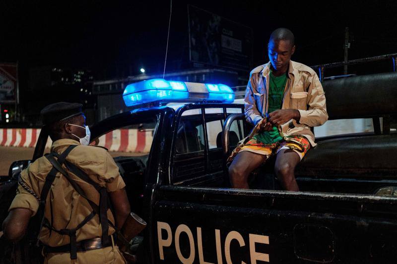 Varios policías ugandeses y miembros de una fuerza paramilitar compuesta por civiles patrullan por las noches en la ciudad de Kampala para asegurarse del cumplimiento del toque de queda nocturno decretado el 14 de abril en Uganda para tratar de detener la propagación del coronavirus. 