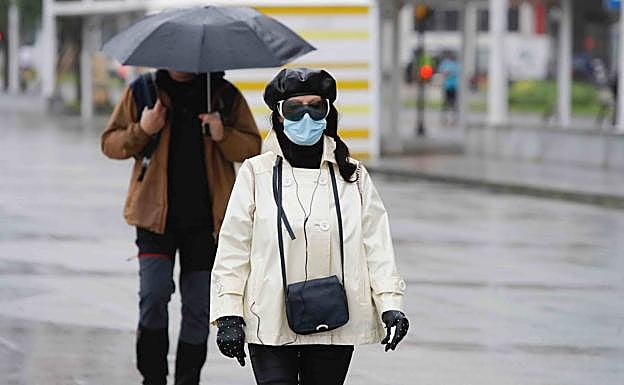 Foto: gijoneses paseando por la playa de San Lorenzo bajo la lluvia. Vídeo: fuerte tormenta esta tarde en Oviedo. 