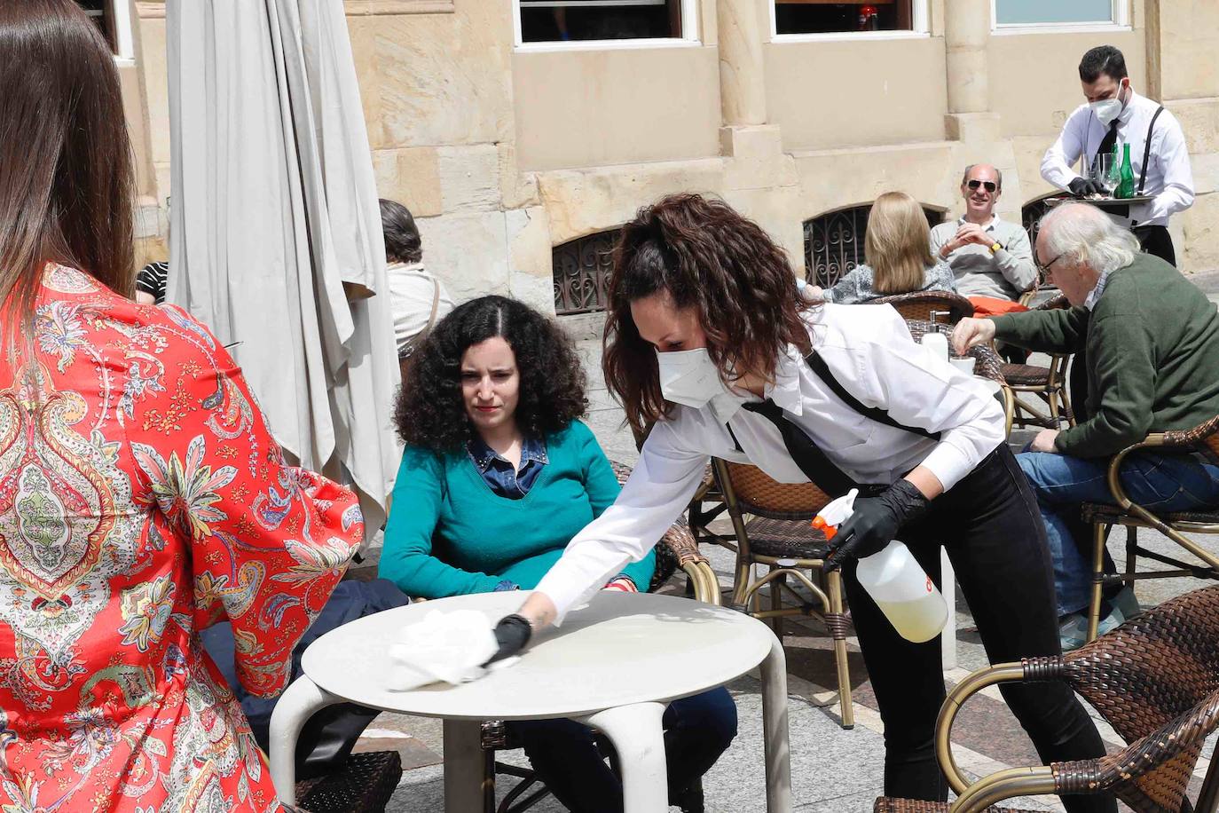 Tras ocho semanas con las verjas bajadas y las sillas y mesas apiladas, los establecimientos hosteleros de Gijón han vuelto a colocar sus terrazas. Eso sí, bajo estrictas medidas de higiene y aforo para prevenir el contagio de coronavirus. 