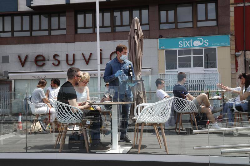 Tras ocho semanas con las verjas bajadas y las sillas y mesas apiladas, los establecimientos hosteleros de Gijón han vuelto a colocar sus terrazas. Eso sí, bajo estrictas medidas de higiene y aforo para prevenir el contagio de coronavirus. 