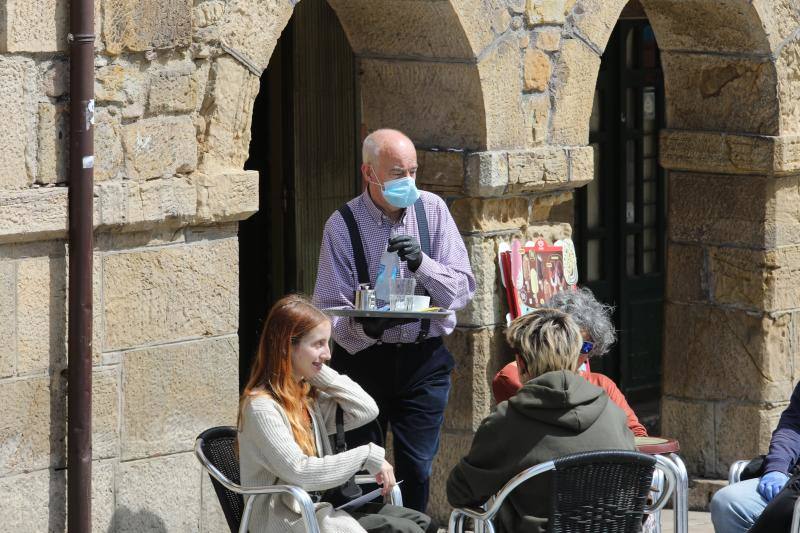 Por primera vez desde que se declaró el estado de alarma por la pandemia de coronavirus los asturianos han podido acudir a las terrazas de bares y cafeterías. Este lunes ha comenzado la fase 1 de la desescalada en el Principado y una de las medidas de alivio del confinamiento es la apertura de terrazas, aunque los establecimientos hosteleros deben acatar estrictas medidas de precaución, como la limpieza exhaustiva de las sillas y mesas o la limitación de aforo. 