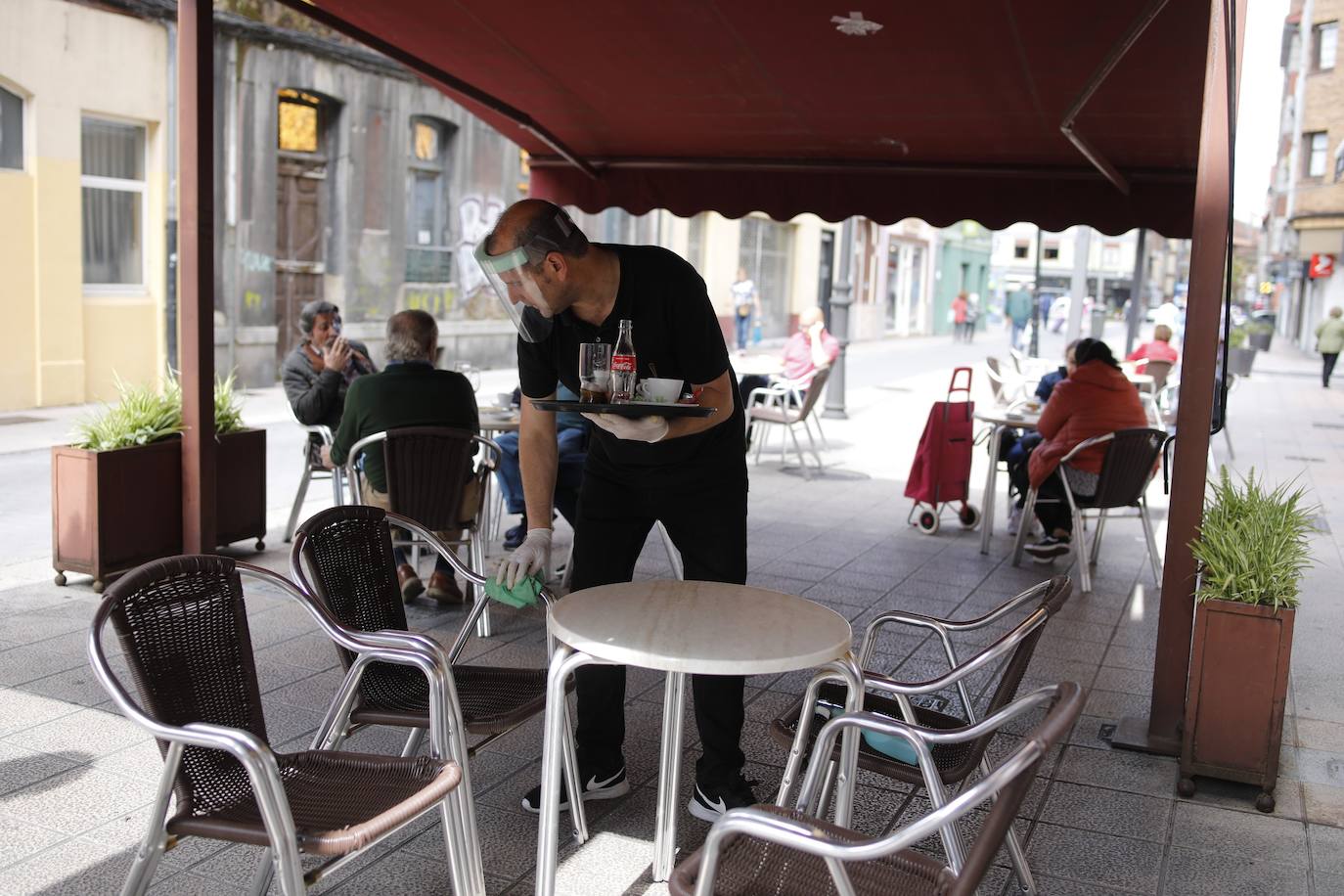 Por primera vez desde que se declaró el estado de alarma por la pandemia de coronavirus los asturianos han podido acudir a las terrazas de bares y cafeterías. Este lunes ha comenzado la fase 1 de la desescalada en el Principado y una de las medidas de alivio del confinamiento es la apertura de terrazas, aunque los establecimientos hosteleros deben acatar estrictas medidas de precaución, como la limpieza exhaustiva de las sillas y mesas o la limitación de aforo. 