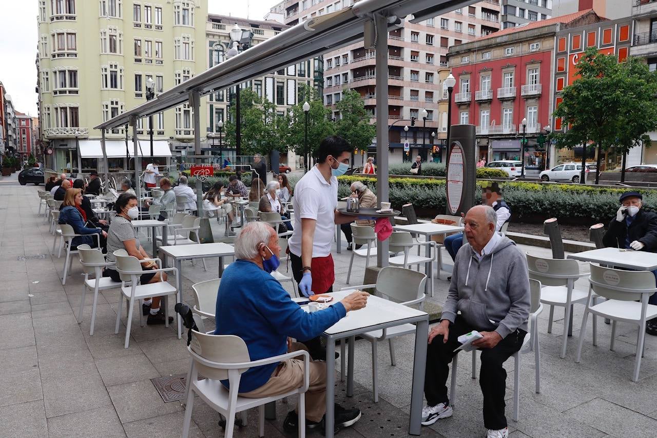 Por primera vez desde que se declaró el estado de alarma por la pandemia de coronavirus los asturianos han podido acudir a las terrazas de bares y cafeterías. Este lunes ha comenzado la fase 1 de la desescalada en el Principado y una de las medidas de alivio del confinamiento es la apertura de terrazas, aunque los establecimientos hosteleros deben acatar estrictas medidas de precaución, como la limpieza exhaustiva de las sillas y mesas o la limitación de aforo. 