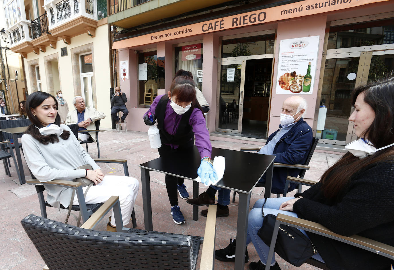 Por primera vez desde que se declaró el estado de alarma por la pandemia de coronavirus los asturianos han podido acudir a las terrazas de bares y cafeterías. Este lunes ha comenzado la fase 1 de la desescalada en el Principado y una de las medidas de alivio del confinamiento es la apertura de terrazas, aunque los establecimientos hosteleros deben acatar estrictas medidas de precaución, como la limpieza exhaustiva de las sillas y mesas o la limitación de aforo. 