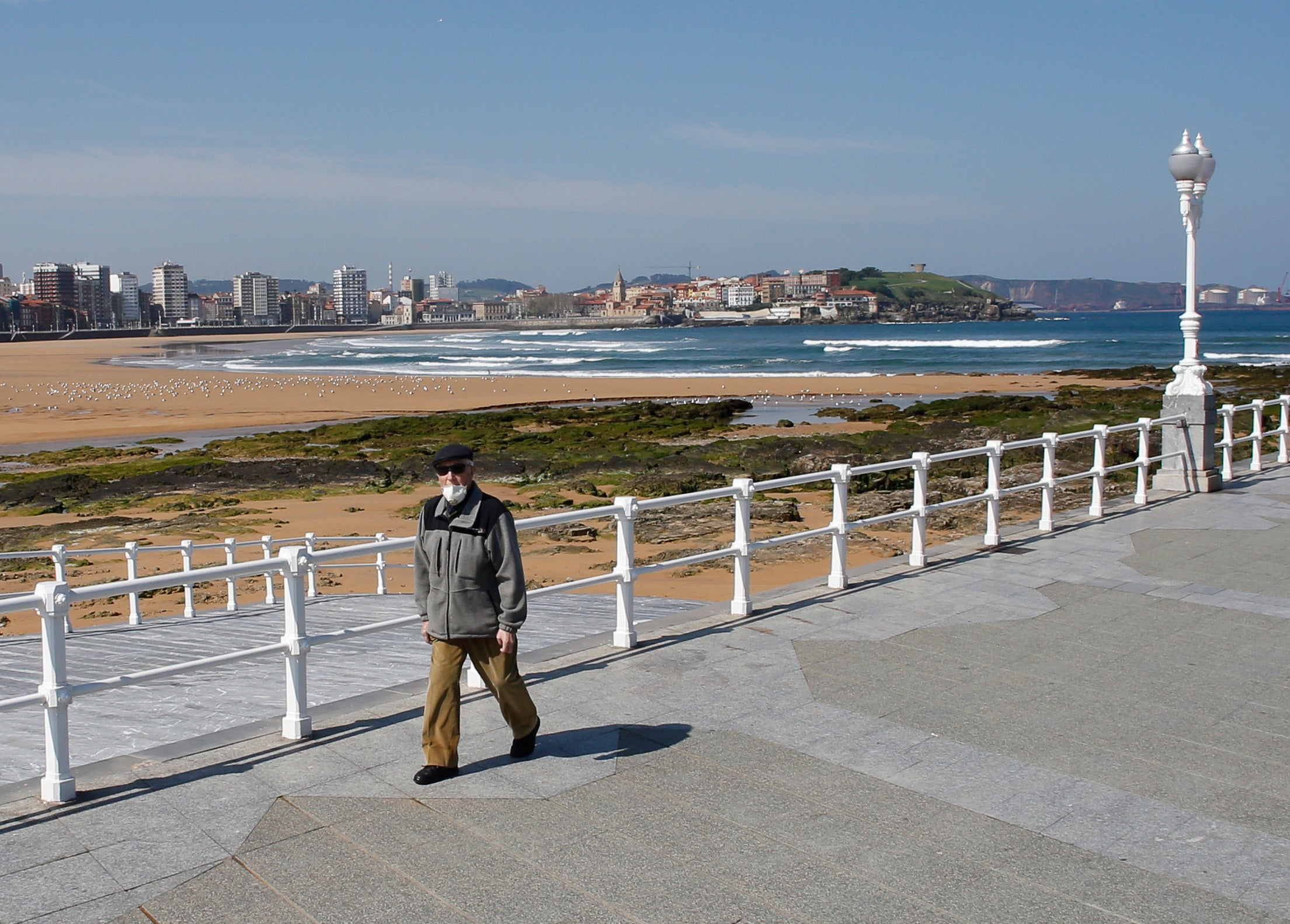 27 de marzo. Gijón | Un hombre con una mascarilla pasea por Gijón.