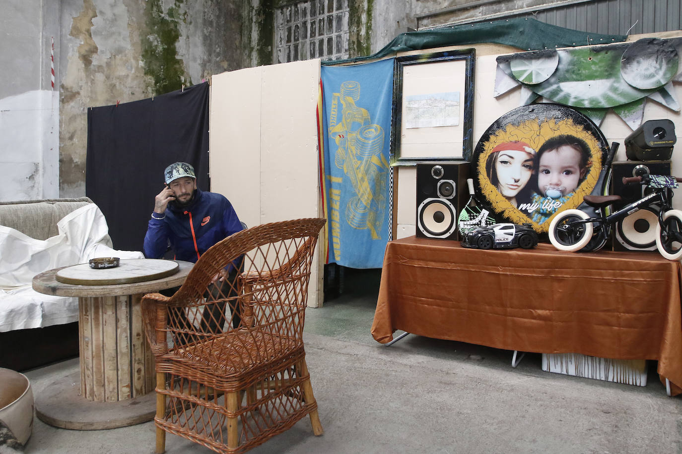 08 de abril. Gijón | Ramón Rivas habla por teléfono sentado en el ‘cuarto de estar’ que ha habilitado en la nave abanonada