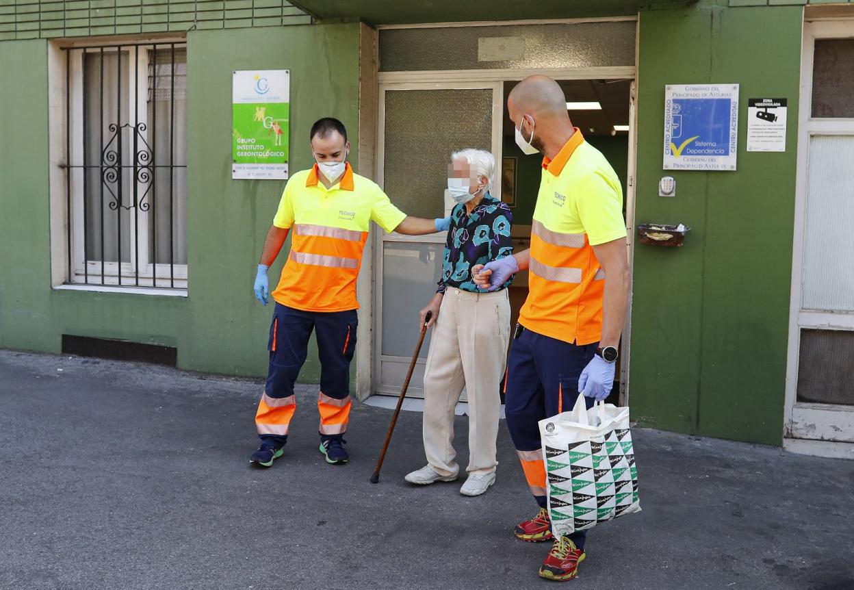 Una de las usuarias del centro de mayores gijonés es trasladada por personal sanitario. 