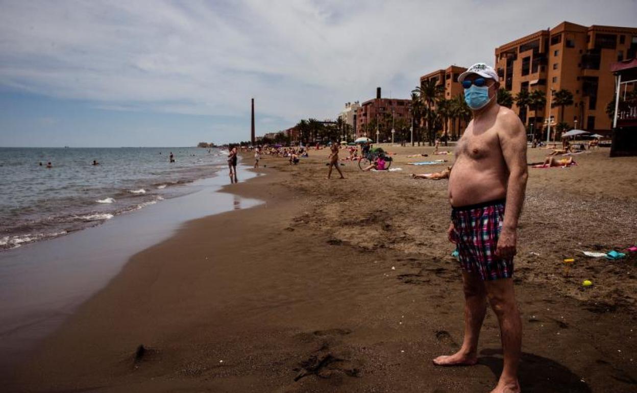 Un hombre con mascarilla en la arena de la Misericordia de Málaga.
