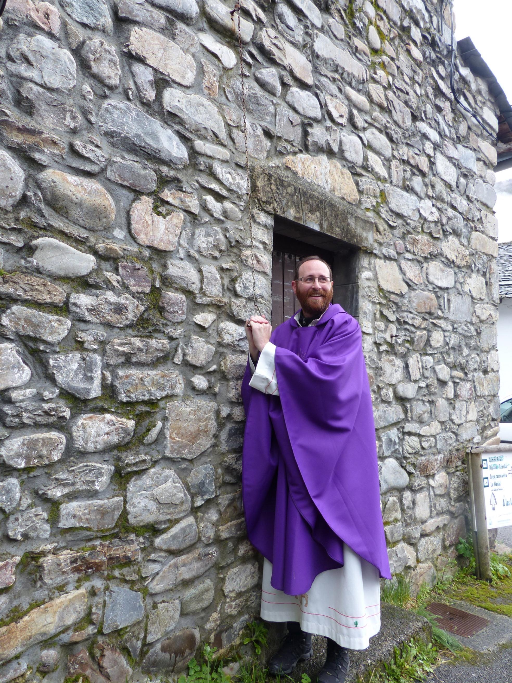 uDegaña. El padre David Cueto llama a misa con la campana de la ermita, en la primera de las tres celebraciones que oficiará durante la mañana del domingo. 