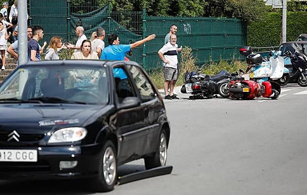 Varios testigos, junto a las motos derribadas y el coche estacionado contra el que chocó el detenido. 
