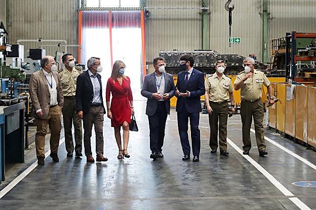 En el centro, Rosana Prada, Juan Escriña y Enrique Fernández, acompañados de la inspección militar, visitan el taller de mecanizado de la fábrica de armas de Trubia. 