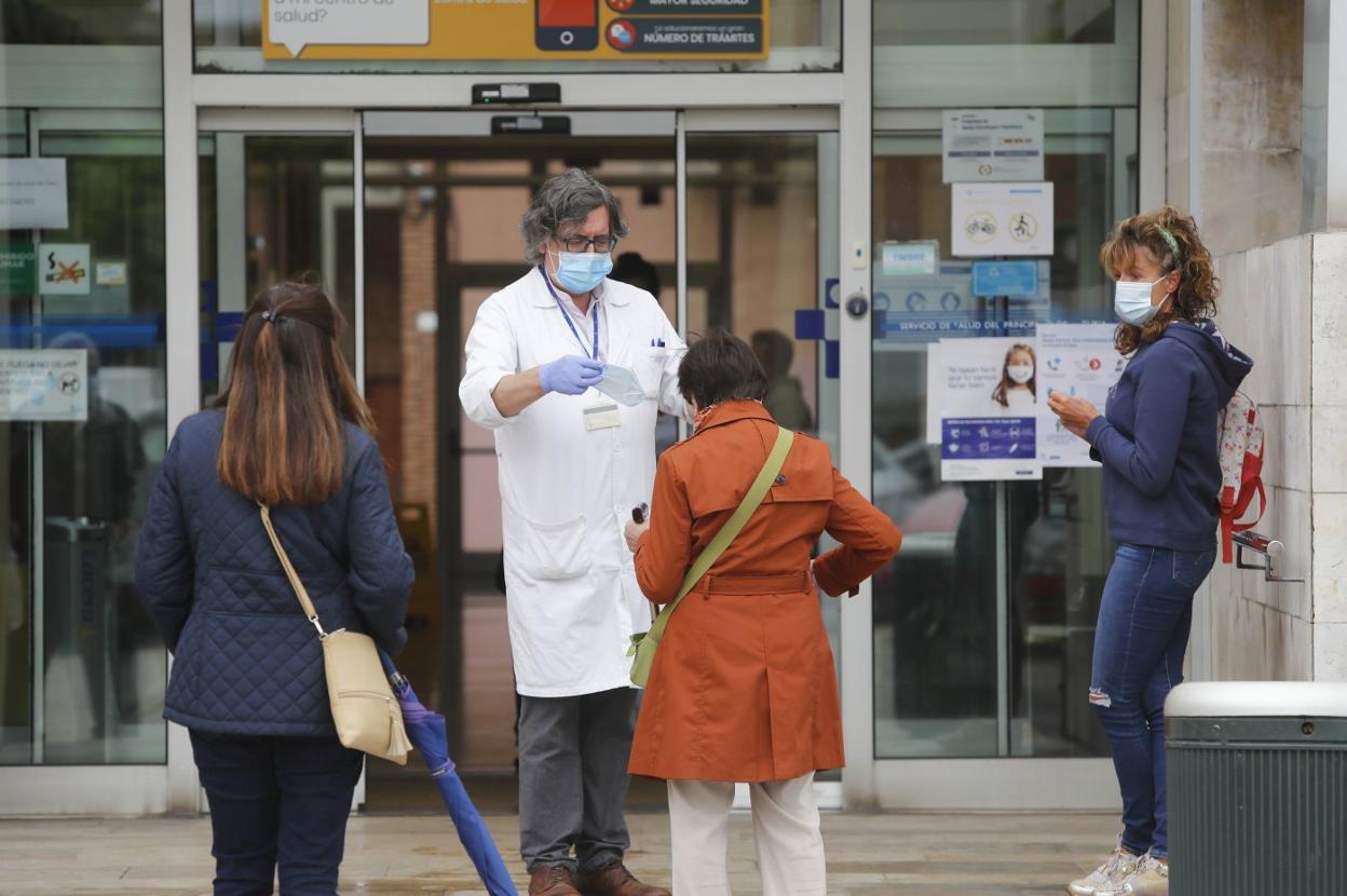 Personal del centro de salud de El Llano, en Gijón, entrega una mascarilla a una paciente. 
