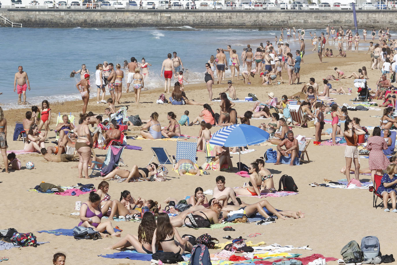 Los arenales gijoneses han vuelto este martes a llenarse de gente que ha querido pasar una nueva jornada de intenso calor tumbado en la arena o refrescándose en el agua.