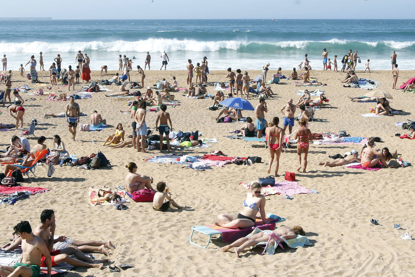 Los arenales gijoneses han vuelto este martes a llenarse de gente que ha querido pasar una nueva jornada de intenso calor tumbado en la arena o refrescándose en el agua.