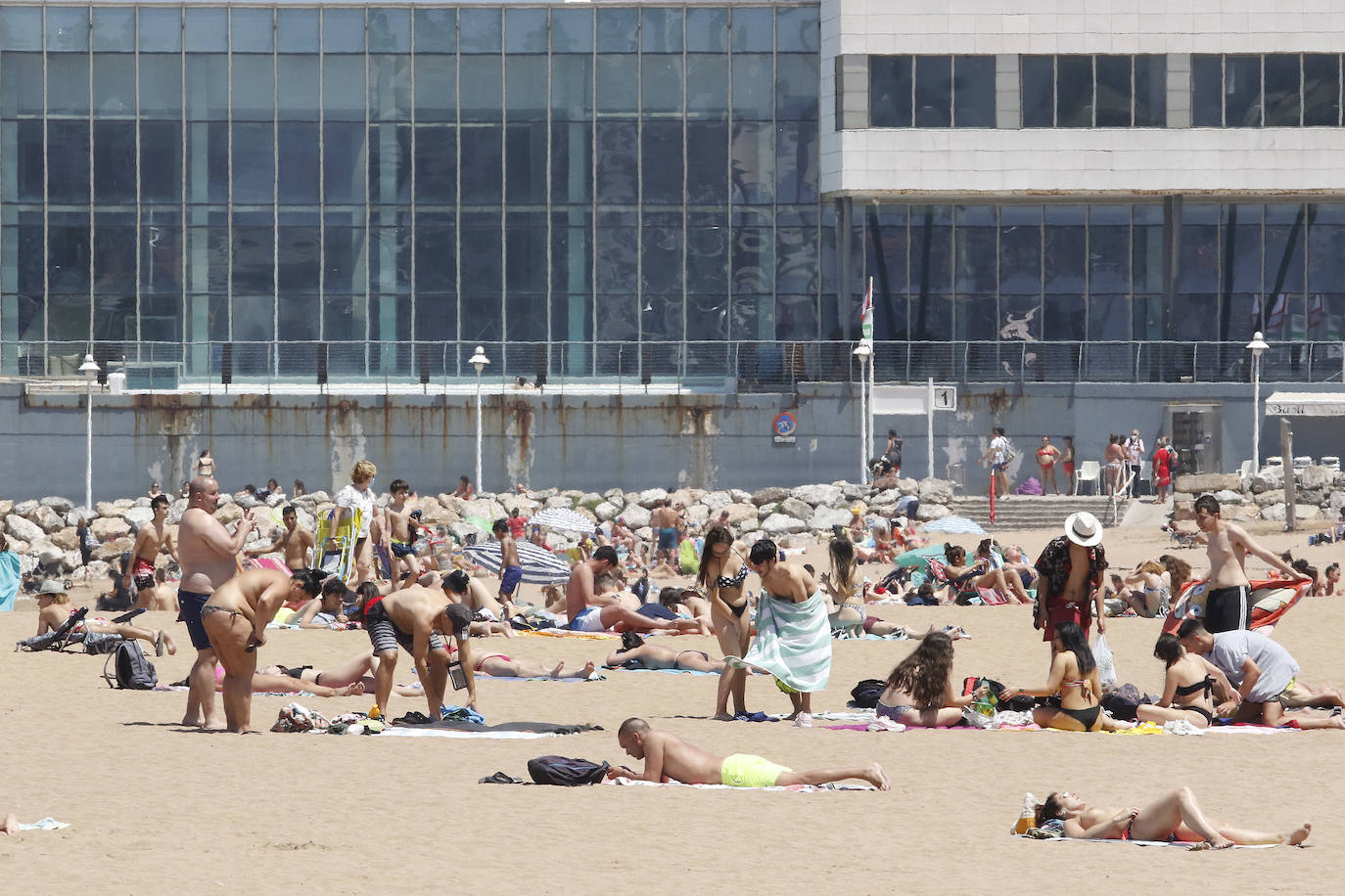 Los arenales gijoneses han vuelto este martes a llenarse de gente que ha querido pasar una nueva jornada de intenso calor tumbado en la arena o refrescándose en el agua.