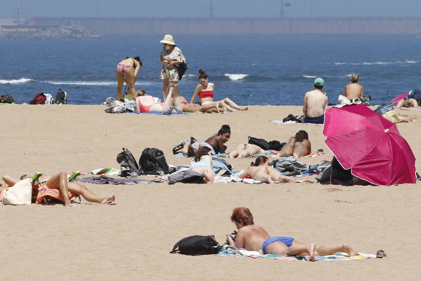 Los arenales gijoneses han vuelto este martes a llenarse de gente que ha querido pasar una nueva jornada de intenso calor tumbado en la arena o refrescándose en el agua.