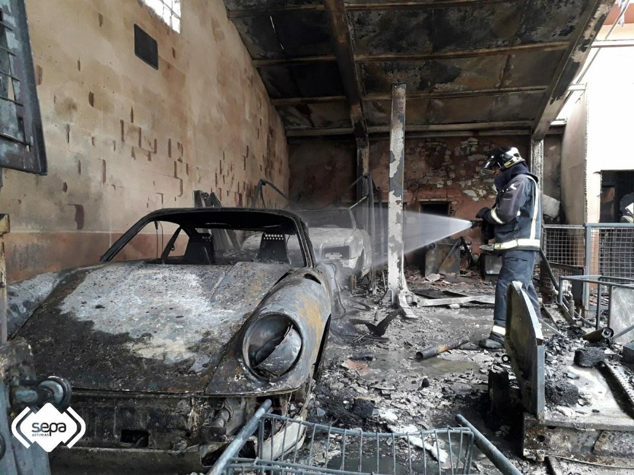 Uno de los bomberos desplazados a la zona trabajando ante uno de los tres coches incendiados en el garaje de ribera de Arriba. 