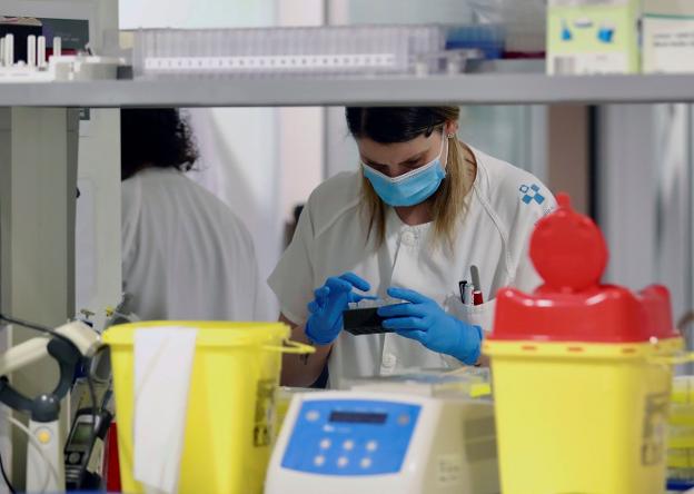En la imagen, técnicos en el Laboratorio de Virología del Hospital Universitario Central de Asturias. En el vídeo, explicación de cómo debe utilizarse la mascarilla.