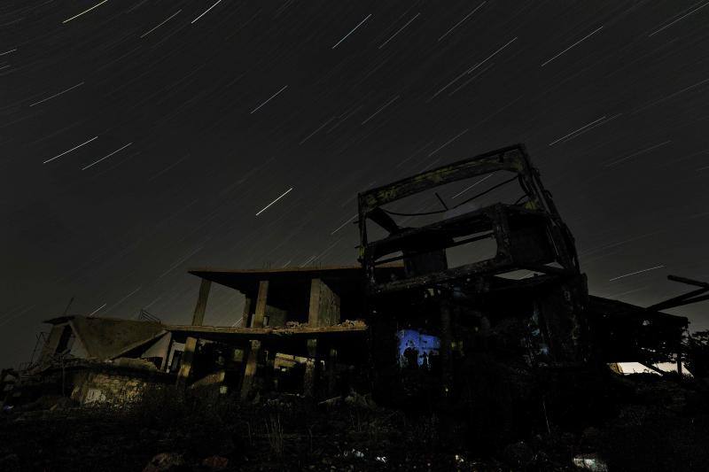 Parece que el mundo se detiene al observar el cielo estrellado de Idlib (Siria). Sin embargo, basta con bajar un poco la mirada para darse cuenta de la realidad: edificios destruidos por una guerra que comenzó hace más de nueve años y que parece no tener fin, un campamento para sirios desplazados, un parque de atracciones abandonado y combatientes a lo largo de la primera línea con las fuerzas gubernamentales. Así son las noches en la provincia de Idlib, controlada por los rebeldes sirios. 