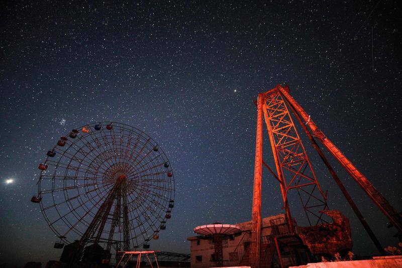 Parece que el mundo se detiene al observar el cielo estrellado de Idlib (Siria). Sin embargo, basta con bajar un poco la mirada para darse cuenta de la realidad: edificios destruidos por una guerra que comenzó hace más de nueve años y que parece no tener fin, un campamento para sirios desplazados, un parque de atracciones abandonado y combatientes a lo largo de la primera línea con las fuerzas gubernamentales. Así son las noches en la provincia de Idlib, controlada por los rebeldes sirios. 