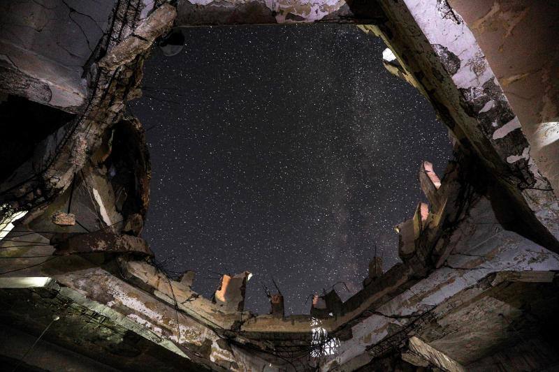 Parece que el mundo se detiene al observar el cielo estrellado de Idlib (Siria). Sin embargo, basta con bajar un poco la mirada para darse cuenta de la realidad: edificios destruidos por una guerra que comenzó hace más de nueve años y que parece no tener fin, un campamento para sirios desplazados, un parque de atracciones abandonado y combatientes a lo largo de la primera línea con las fuerzas gubernamentales. Así son las noches en la provincia de Idlib, controlada por los rebeldes sirios. 