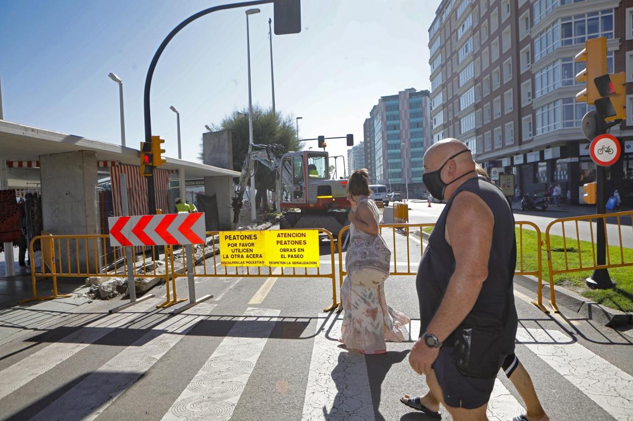Peatones junto a las vallas que cierran parte de la calzada. 