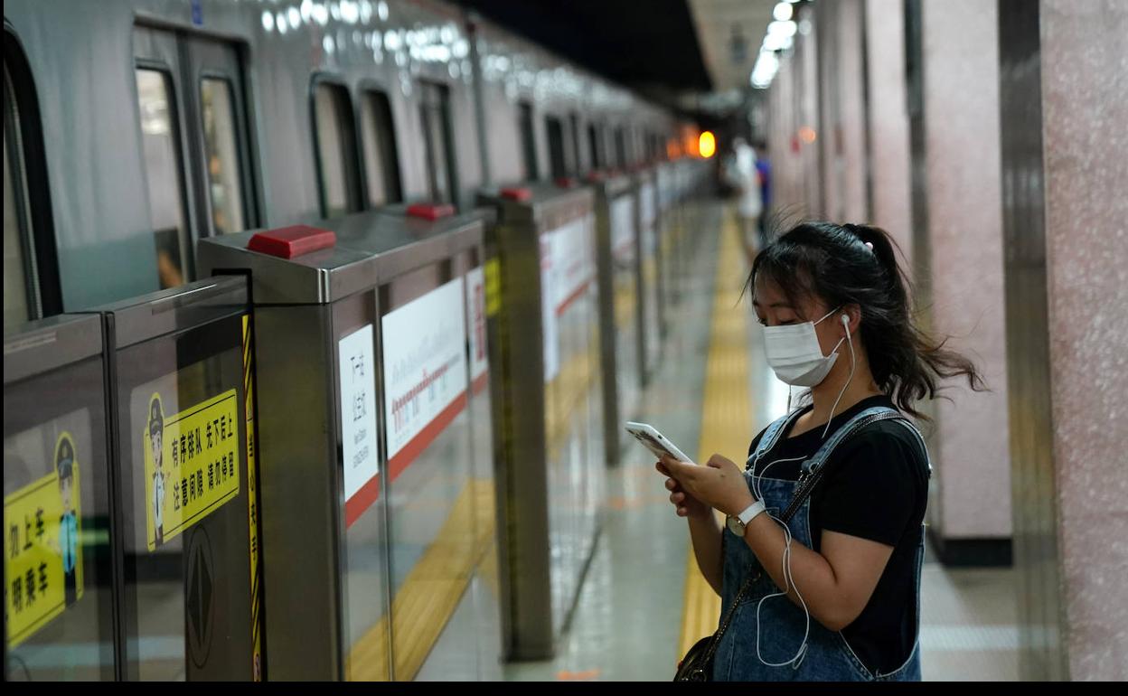 Una mujer china, con mascarilla, en el metro