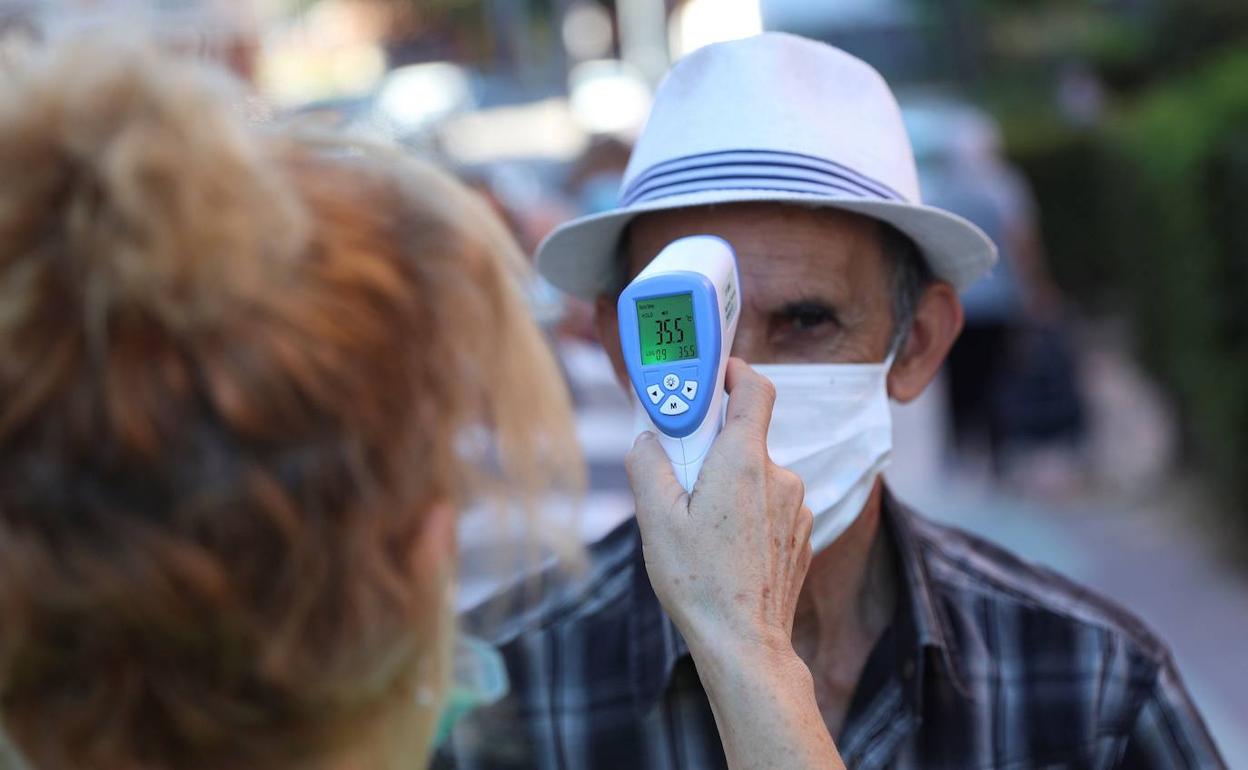 Una voluntaria toma la temperatura a un hombre en el mercadillo de la localidad madrileña de Fuenlabrada. 