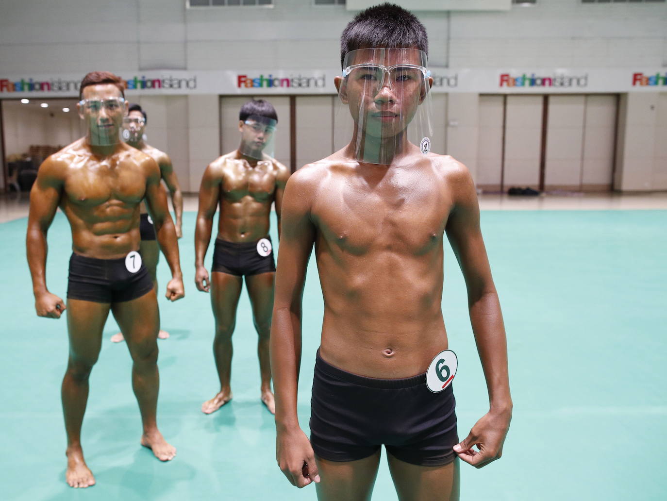 Protegidos con pantallas de plástico, decenas de concursantes compiten en el certamen de culturismo 'Mr. Tailandia' en Bangkok