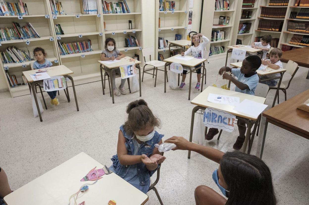 Separación de mesas e higiene de manos en el colegio Asturias de Gijón, con niños participantes en el programa '11x12'. 