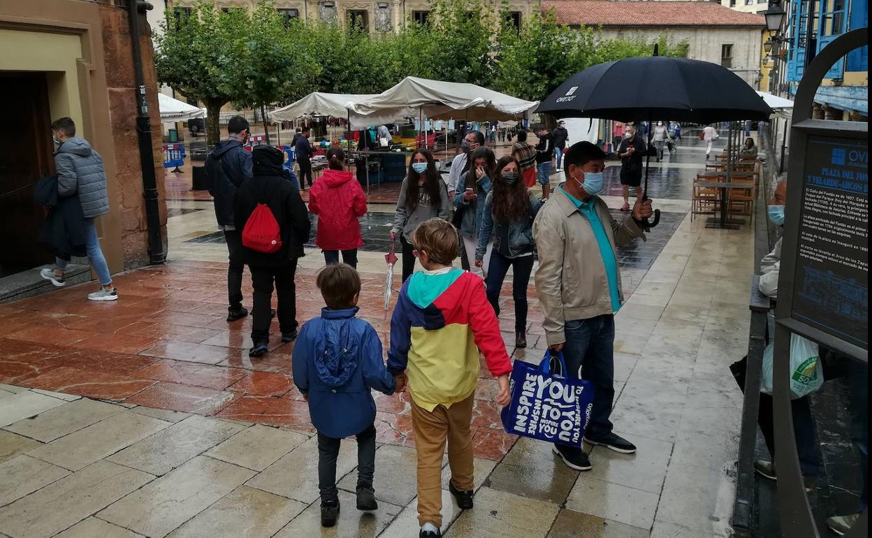 Varias personas pasean por Oviedo bajo una intensa lluvia. 