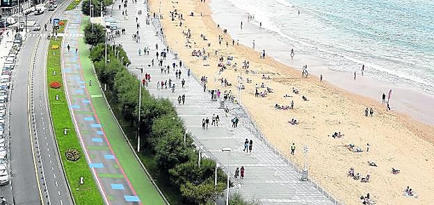 Vista general del paseo del Muro y de la playa de San Lorenzo, con la zona de la calzada reservada a los peatones pintada de verde y azul. 