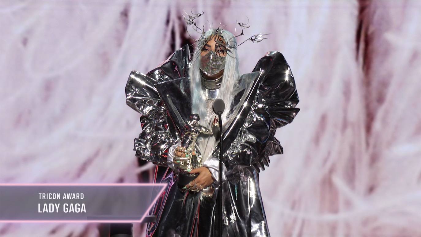 Lady Gaga fue la protagonista absoluta de la gala de los MTV Video Music Awards (VMA) 2020, no solo por los cinco galardones que se llevó, entre ellos el de artista del año, sino también por las sorprendentes mascarillas que lució en cada una de sus apariciones. La primera que llamó la atención fue una gran mascarilla rosas con alambres y malla metálica, pero después impactó con otra negra que tapaba prácticamente toda la cara y que en la zona frontal tenía una pequeña pantalla de luces que cambiaban de color. Más tarde, lució una de cuero decorada con largos cuernos en los laterales y pinchos metálicos. Esas fueron solo tres de las numerosas que usó para recoger sus cinco premios de la noche. Y es que, además de ser nombrada artista del año, recibió premios por 'Rain on Me', su proyecto con Ariana Grande: mejor colaboración, canción del año, y mejor fotografía. Además, se embolsó el primer premio 'Tricon' que se entrega en los VMAs, que reconoce el talento de un artista en tres o más disciplinas distintas. 