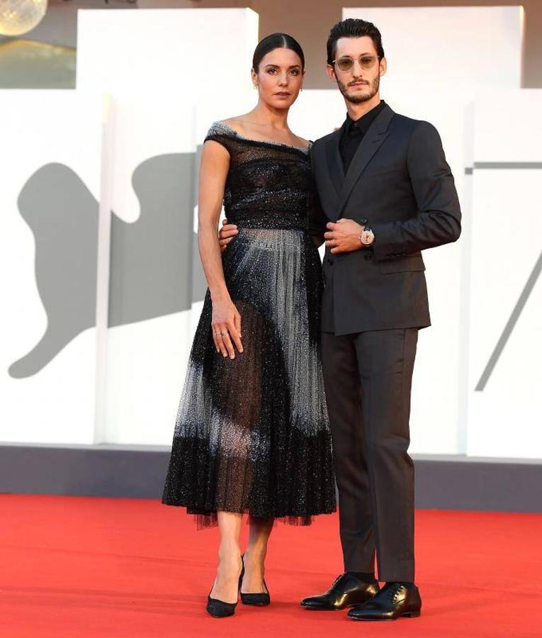 Pierre Niney de nuevo junto a Natasha Andrews que se decantó por un vestido midi de diseño plisado y con brillos en tono negro y gris claro.