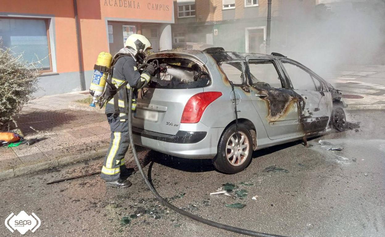 Un bombero, en las labores de extinción del fuego que calcinó un vehículo en Tapia del Casariego 