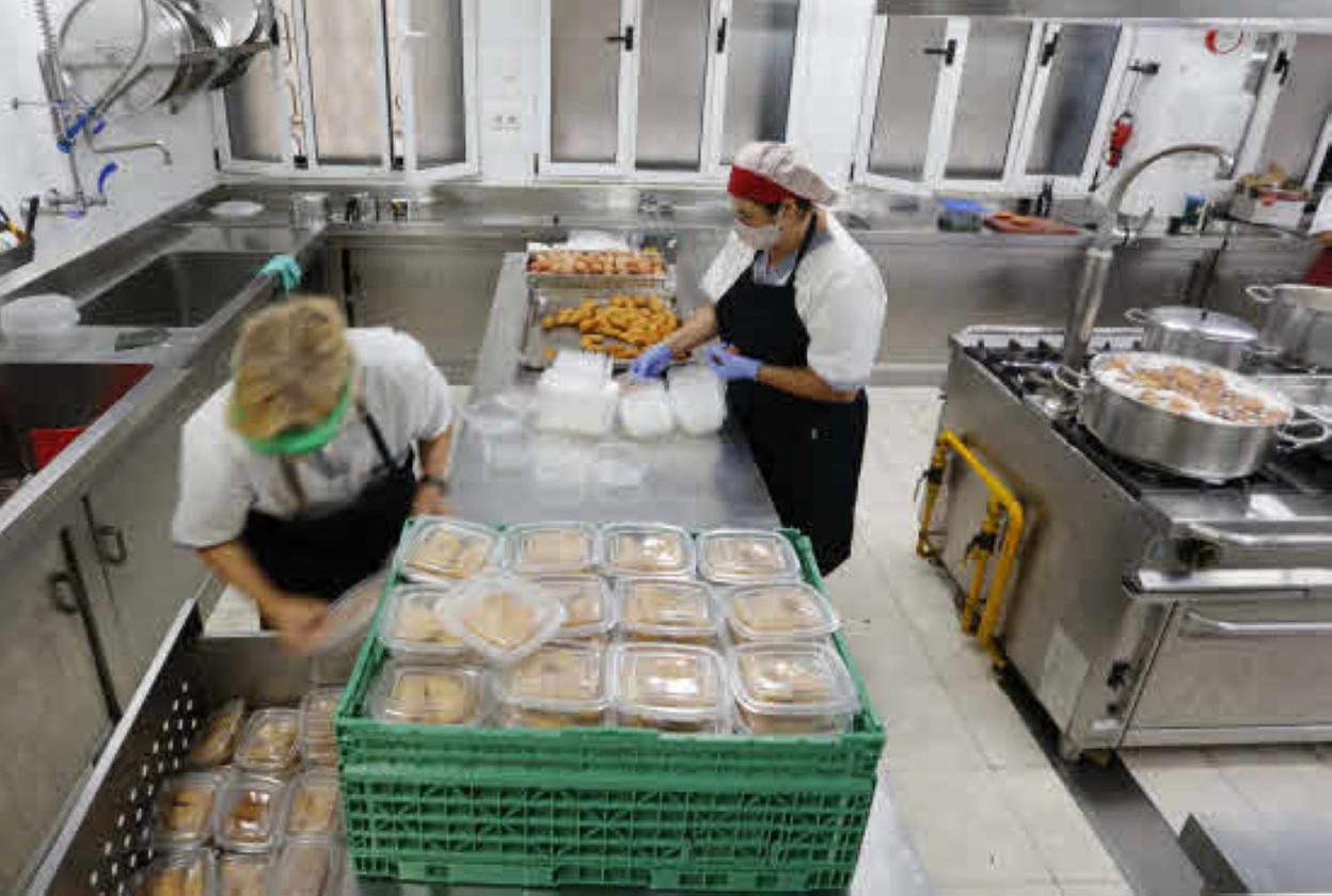 Dos trabajadoras de la Cocina Económica preparan los envases de comida que se entregan para llevar. 